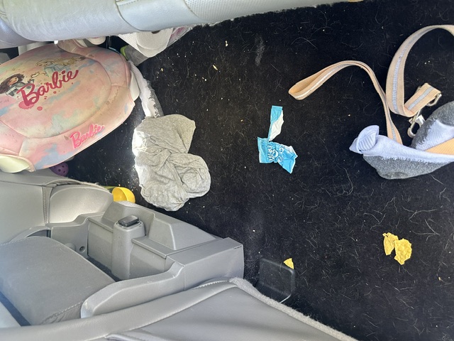 Before interior detailing: rear floor covered with kids toys, trash and debris in a Ford F-150 Lariat